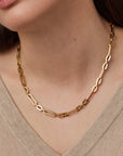 Gold chain necklace worn by a person with a neutral background
