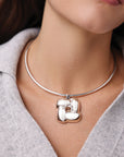 Silver necklace with a unique pendant worn by a person