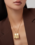 Gold necklace with a pendant worn by a person against a neutral background