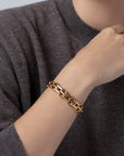 Gold chain bracelet on a wrist with a gray sweater background