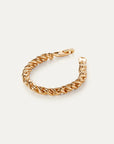 Gold braided bracelet on a light beige background