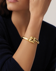 Gold bracelet on a person's wrist with a neutral background