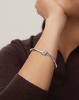 Silver bracelet on a person's wrist with a neutral background
