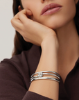 Woman wearing a silver bracelet on her wrist with a neutral background