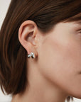 Close-up of a person wearing a silver hoop earring with a blurred background