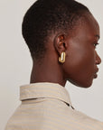 model wearing gold earrings on a white background