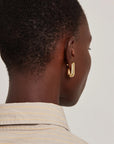 model wearing gold earrings on a white background