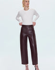 Woman wearing a white top and brown leather pants on a white background front view