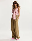 Woman wearing a pink floral top and beige pants on a white background