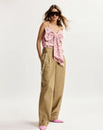 Woman wearing a pink floral top and beige pants on a white background