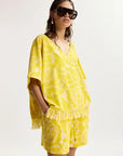 Woman wearing a yellow matching set with sunglasses on a white background