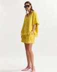 Woman wearing a yellow matching set with sunglasses on a white background