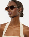 Woman wearing sunglasses and a white DRESS against a plain background
