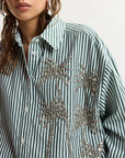 Striped shirt with palm tree designs and sequins on a plain background