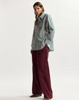 Woman wearing a striped shirt and burgundy pants on a white background