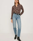 Woman wearing a patterned blouse, jeans, and black boots on a white background front view