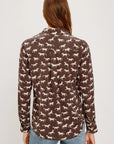 Woman wearing a brown shirt with horse pattern on a white background back view
