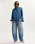 Person wearing a blue denim outfit with floral embellishments on a white background