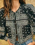 Person wearing a black bandana print shirt with a blurred background