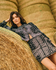 Woman in a black and white patterned outfit lying on hay bales.