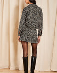 model wearing a zebra jacket and skirt on a cream background