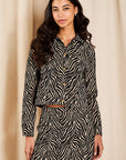 model wearing a zebra jacket top and mini skirt on a cream background