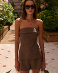 Woman wearing a brown strapless top and shorts set in an outdoor setting.