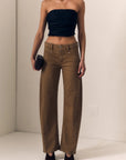 Woman wearing a black strapless top and brown wide-leg pants against a plain background