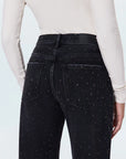 Black jeans with white speckles worn by a person on a light gray background