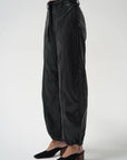A model is shown from the waist down wearing black wide-leg harem pants with a drawstring waist and black mule heels, set against a plain light gray studio background.