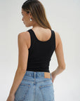 Person wearing a black tank top and blue jeans on a white background back view