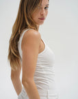 Woman wearing a white sleeveless top against a plain background