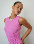 Woman wearing a pink sleeveless top against a plain background