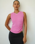 Person wearing a pink sleeveless top and black skirt against a white background