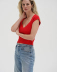 Woman wearing a red top and blue jeans on a white background