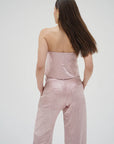 Woman wearing a pink strapless top and pants on a white background