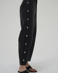 Black pants with white buttons on a gray background side view