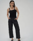 Woman wearing a black sleeveless top and black pants on a white background front view