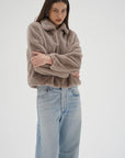 Woman wearing a brown sweater and light blue jeans on a white background