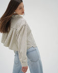Woman wearing a striped shirt and light blue jeans on a white background