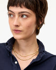 Woman wearing gold necklaces and earrings on a white background