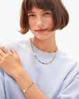 Woman wearing a colorful beaded necklace and bracelet on a plain background