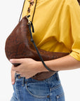 a model in a yellow shirt and jeans wearing the python lune bag on a white background