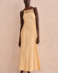 Woman wearing a pale yellow dress with lace details against a plain background, front