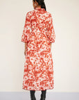 Person wearing a red and white floral dress on a plain background, back