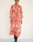 Woman wearing a red and white patterned dress on a white background, front