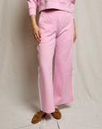 Person wearing a pink outfit with wide-leg pants on a plain background