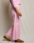 Person wearing a pink outfit with wide-leg pants on a plain background