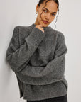 model wearing a grey sweater with black jeans on a grey background