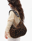 Person wearing a leopard print handbag on a white background
